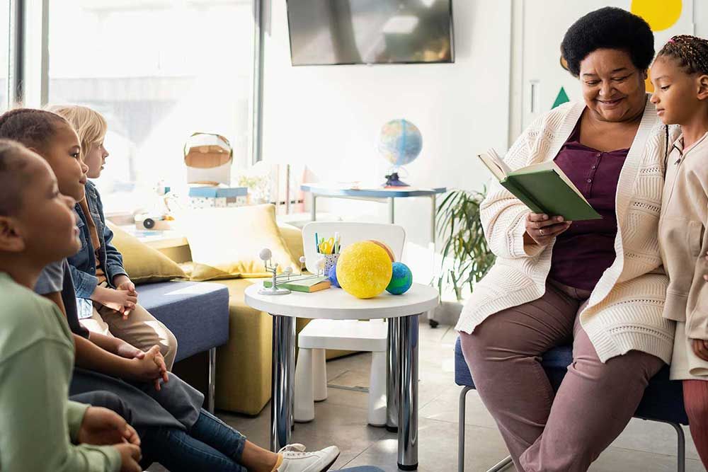 Caregiver reading with children in a bright playroom