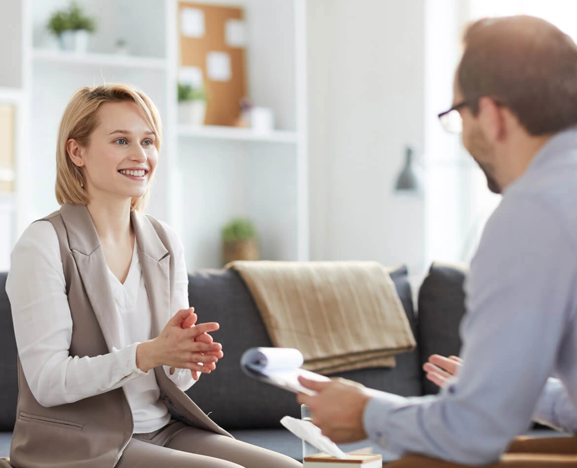 Woman smiling as she talks with a therapist seated across from her